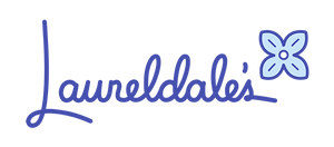 Our logo is comprised of the word Laureldale’s in a custom hand written font in indigo color, with a stylized four petal laurel tree flower in a lighter indigo color placed to the right of the s.